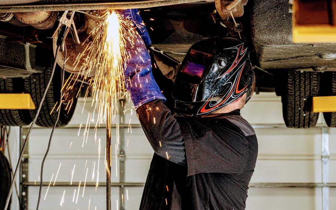 Stream RV technician welding under a motorhome on the lift in our Creedmoor, NC service shop